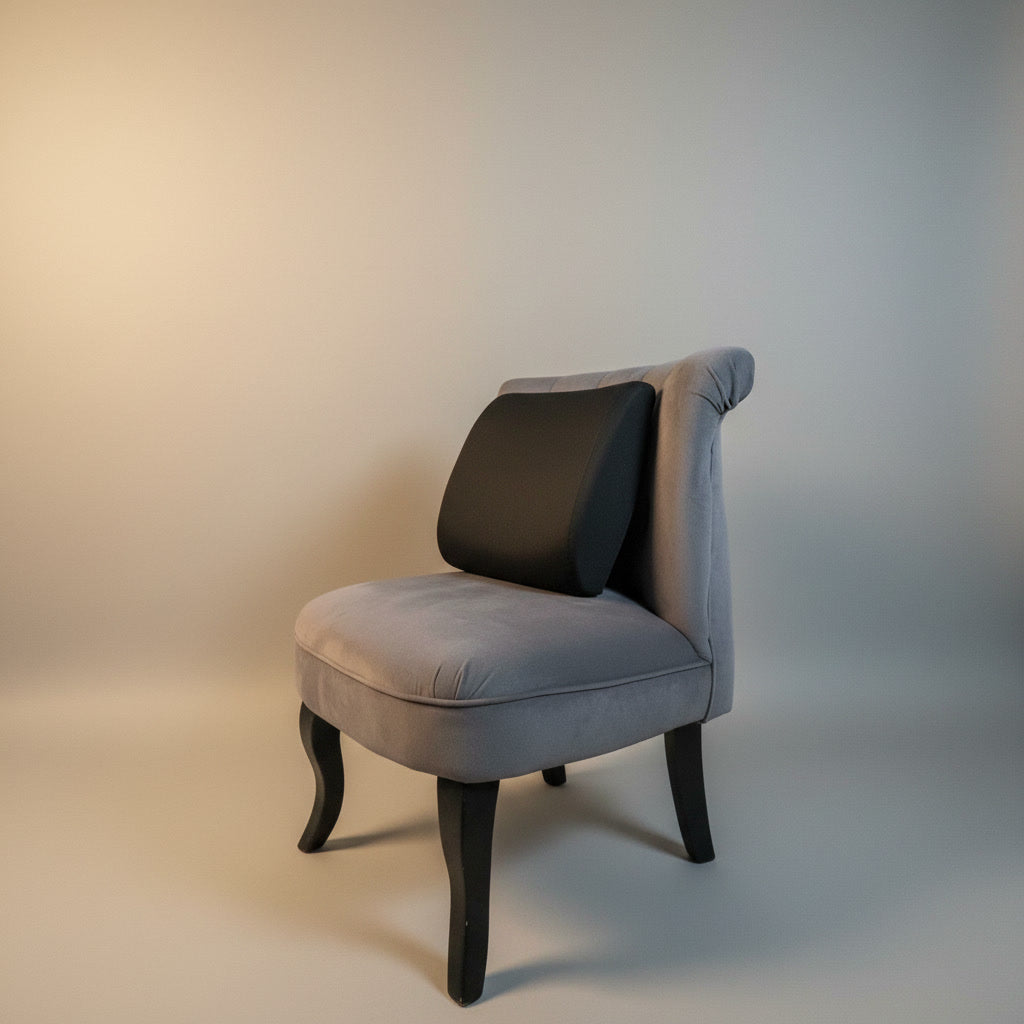 Coussin lombaire noir posé sur un fauteuil de salon 
gris pour soutien du bas du dos à la maison